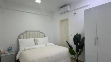 Une chambre à coucher comprenant un lit, une table de chevet, une armoire et un ventilateur de plafond.