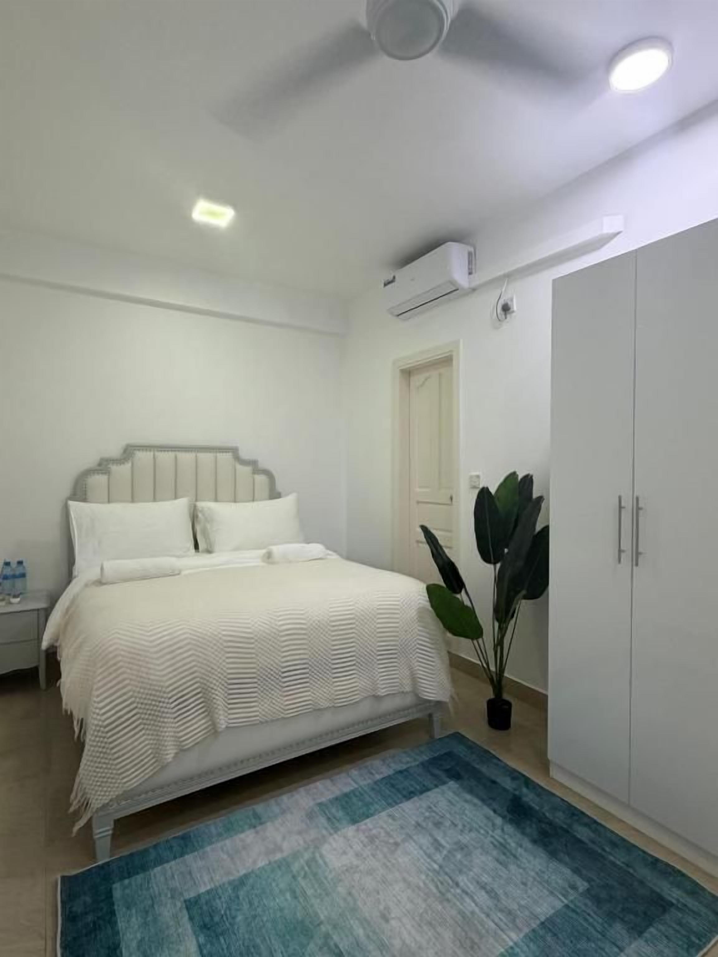 Een slaapkamer met een bed, nachtkastje, garderobe en een kamerplant.