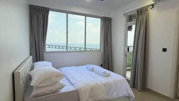 Un dormitorio moderno con cama, ventilador de techo, ventana con cortinas y una mesita con una botella y vasos.