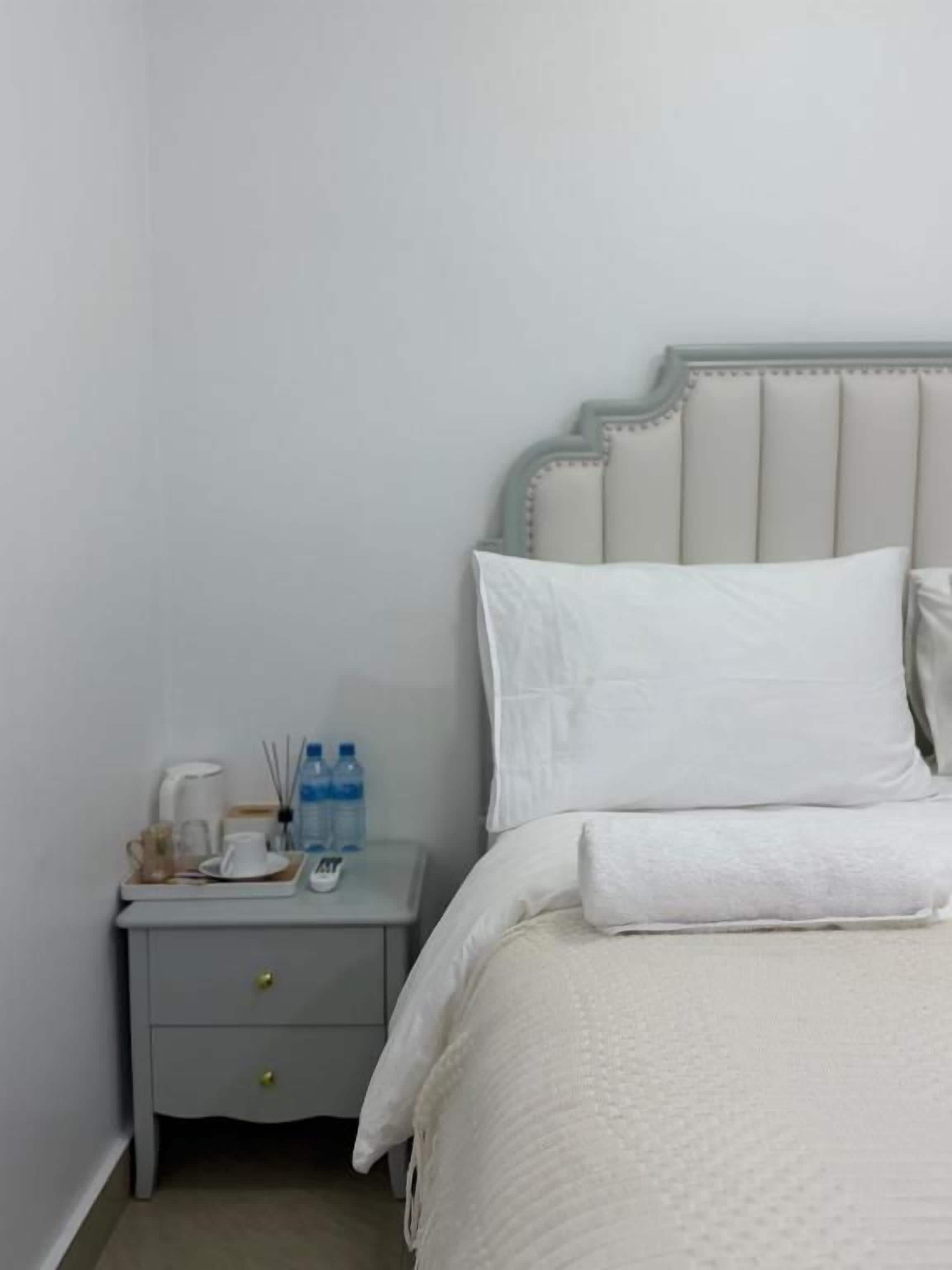 Un dormitorio con una cama, una mesita de noche y un cabecero fijado a la pared.
