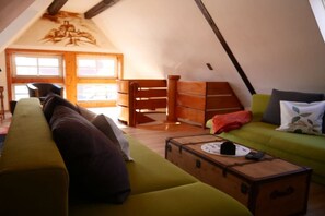 Ein gemütliches Loft-Zimmer mit einem grünen Sofa, einer Holzkiste und einer Holzleiter.
