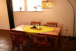 Ein Essbereich mit einem Holztisch, vier Stühlen, einer gelben Tischdecke und einer Stehlampe.