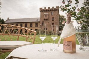 A bottle of Freixenet champagne, two glasses, and a vase with flowers on a table. - Manor House Burg Vlatten - To the Court (Heimbach)