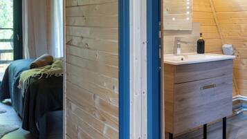 A wooden interior with a bed, a dresser, and a mirror.