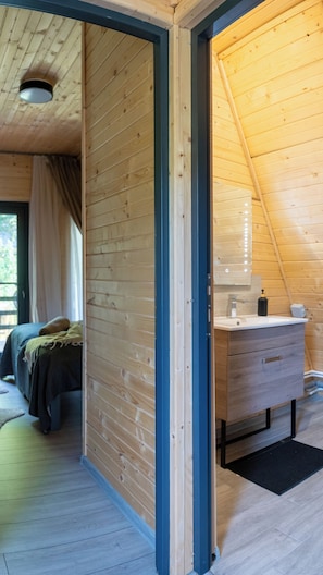A wooden interior with a bed, a dresser, and a mirror.