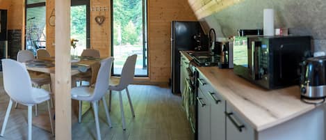 A modern kitchen with wooden cabinetry and a dining area with white chairs.