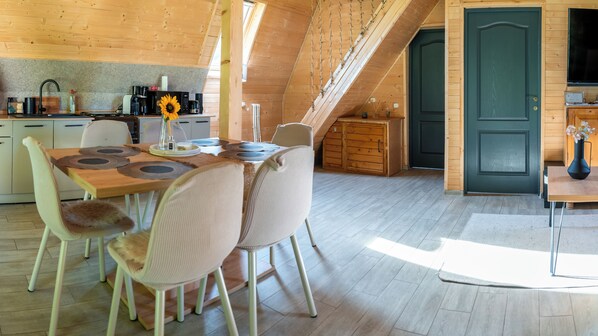 A cozy dining area with a wooden table and chairs, a kitchen with appliances, and a dark door.