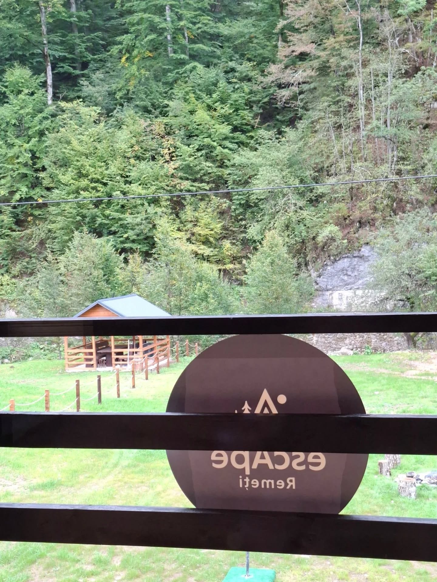 A view of a forested area with a cabin and a sign with the text 'GACBEIT RIMET'.