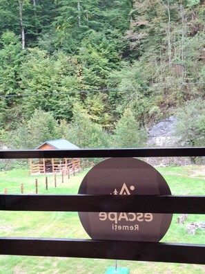 A view of a forested area with a cabin and a sign with the text 'GACBEIT RIMET'.