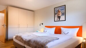 Ein Hotelzimmer mit Bett, Schrank, Nachttisch und einem Poster an der Wand.