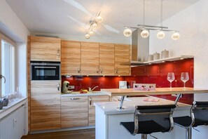 Eine moderne Küche mit Holzausbau, einem Einbauofen und einer Bar mit zwei Stühlen.