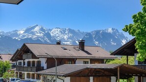 Ein traditionelles Chalet mit geneigtem Dach, Holzbalkonen und Blick auf schneebedeckte Berge.