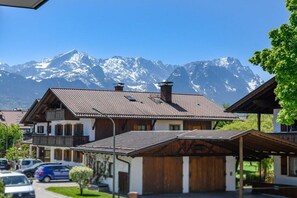 Een klassiek chalet met een schuin dak, houten balkons en uitzicht op besneeuwde bergtoppen.