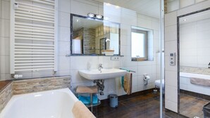 Ein modernes Badezimmer mit Badewanne, Waschbecken, Toilette und Duschbereich.
