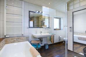 Een moderne badkamer met een bad, een wastafel, een toilet en een douche.
