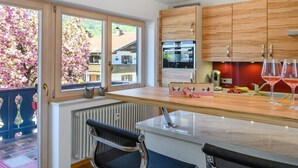 Eine moderne Küche mit Holdekor, einem eingebauten Backofen und einem Fenster mit Blick auf einen Garten voller blühender Blumen.