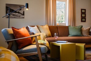 Un salon moderne avec un canapé, un fauteuil et une petite table sur laquelle se trouve un verre de vin.