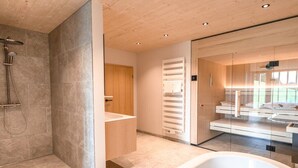 Une salle de bain moderne avec une baignoire sur pieds, un espace douche et un meuble-lavabo avec un encadrement en verre.