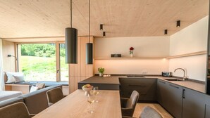 Une cuisine moderne avec une table en bois, des chaises et des luminaires suspendus.