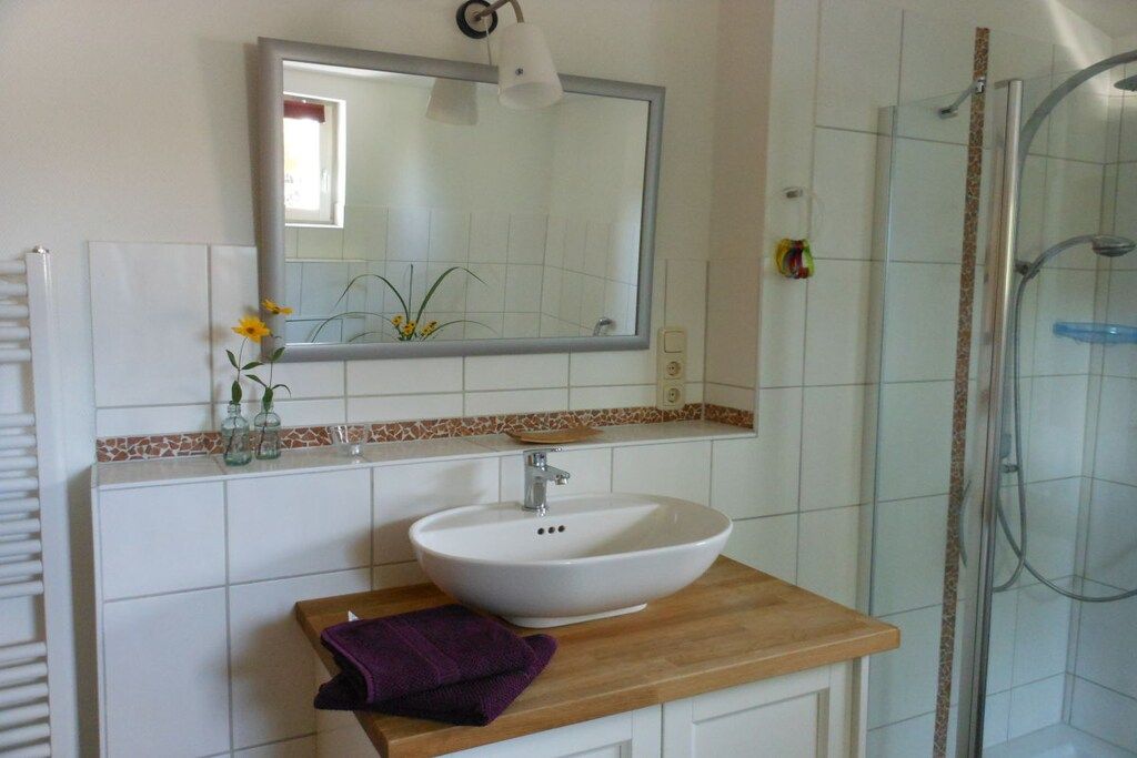 A bathroom with a white sink, mirror, and shower.