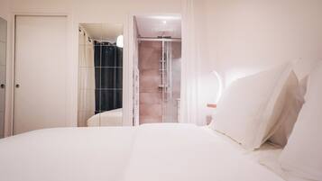 Een hotelkamer met een bed, een douche en een deur naar een andere kamer.
