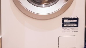 Vista frontal de uma máquina de lavar branca da Electrolux, com painel de controle, um mostrador e etiqueta de certificação Woolmark para lavagem à mão.
