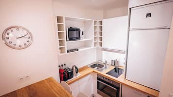 Een kleine keuken met een magnetron, broodrooster, waterkoker en een koelkast.