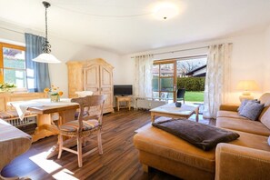 Un salon chaleureux avec un plancher en bois, un canapé, une table à manger avec des chaises et un téléviseur.