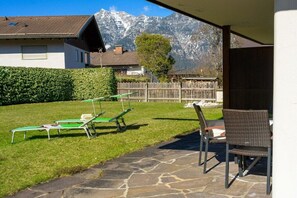 Eine Terrasse mit Steinboden, einem Korbstuhl und einem Tisch.