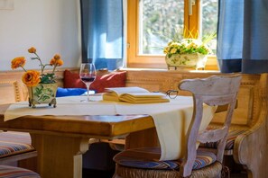A wooden table with a book, a glass of red wine, and a vase with flowers. - Holiday apartment with 1 bedroom (Garmisch-Partenkirchen)