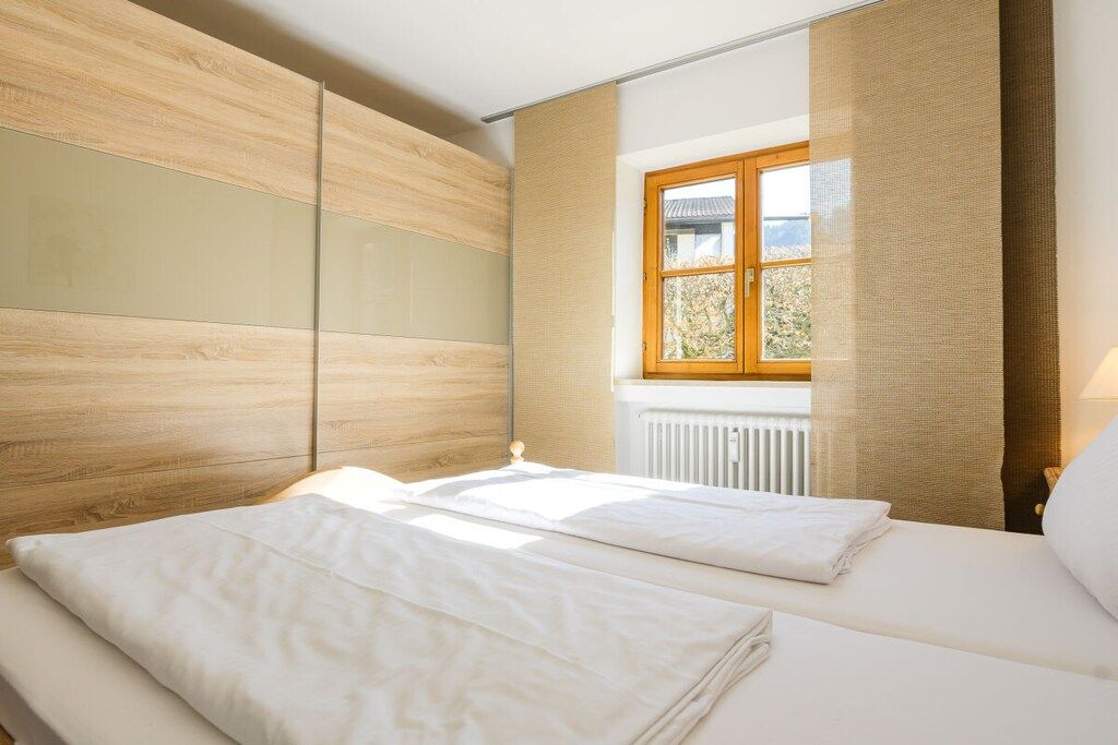 Une chambre d’hôtel avec un lit, une fenêtre avec des rideaux et un radiateur.