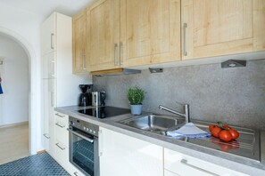Eine moderne Küche mit weißen Schränken, einer Edelstahl-Spüle und einem eingebauten Backofen.