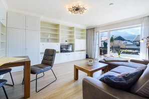 Een moderne woonkamer met een eethoek, inbouwplanken en uitzicht op buiten.