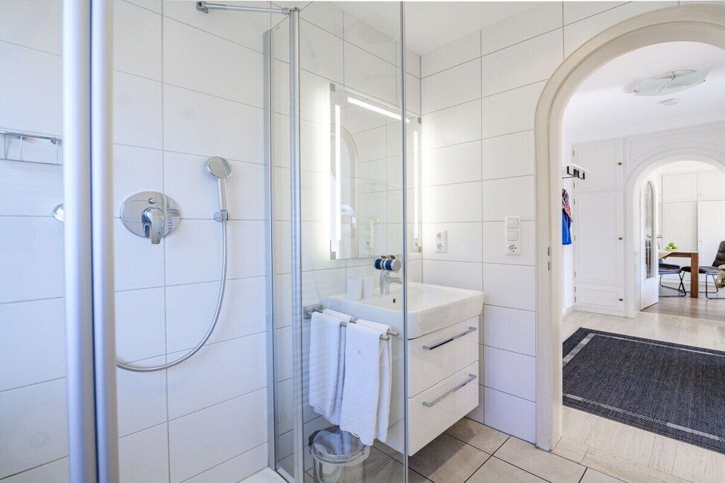 A modern bathroom with a glass-enclosed shower, a white sink, and a mirror.