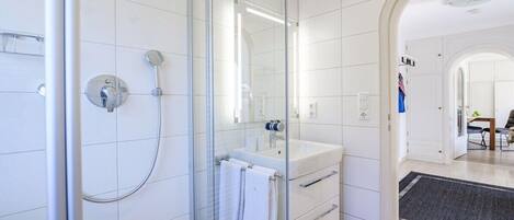 A modern bathroom with a glass-enclosed shower, a white sink, and a mirror.