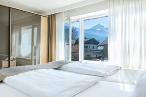 Ein Hotelzimmer mit einem Bett, einem großen Fenster und Blick auf die Berge.
