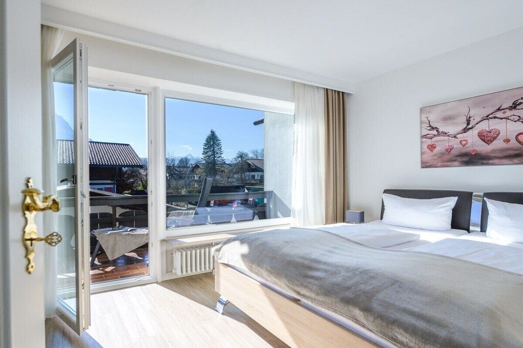 Una camera d'albergo con un letto grande, vista all'esterno e un quadro appeso al muro.