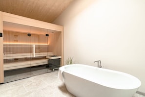 Un bany modern amb una banyera independent, armaris de fusta i una cabina de dutxa de vidre.