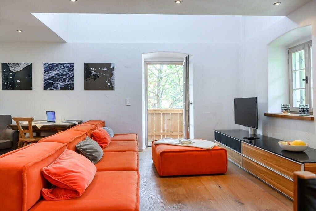A modern living room with a sofa set, a television, and artwork on the wall.