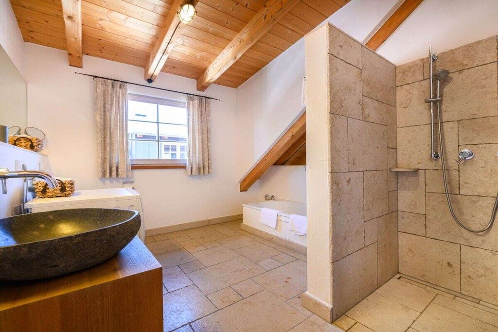 Een badkamer met een wastafel van steen, een bad en een douchehoek.