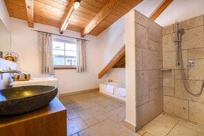 Ein Badezimmer mit einem Steinkonstruktion-Waschbecken, einer Badewanne und einer Duschkabine.