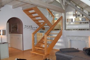 Eine Treppe mit Holzwerteln, ein Kamin und ein Küchenbereich mit Schränken.
