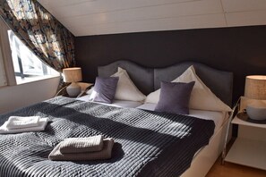 Een moderne slaapkamer met een groot bed, twee nachtkastjes en een raam met gordijnen.