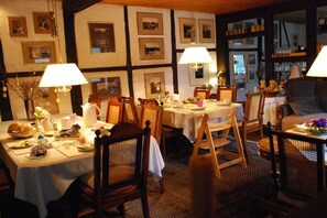 Een eetruimte met meerdere tafels, stoelen en lampen.