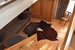 A room with a sofa, a wooden cabinet, a chair, and a leather rug. - at the Bornemann country house (Diemelsee-Adorf)