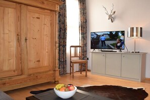 Ein Wohnzimmer mit Fernseher, Holzschrank und Obstschale.
