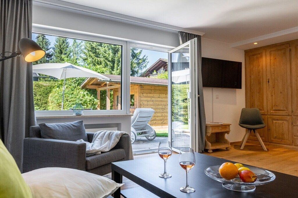 A modern room with a sofa, a dining table with fruit and glasses, and a TV mounted on the wall.
