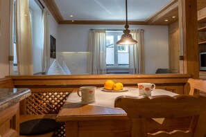 Ein Holztisch mit weißer Tischdecke, zwei Zitronen, eine Tasse und ein Teller mit Blumenmuster.