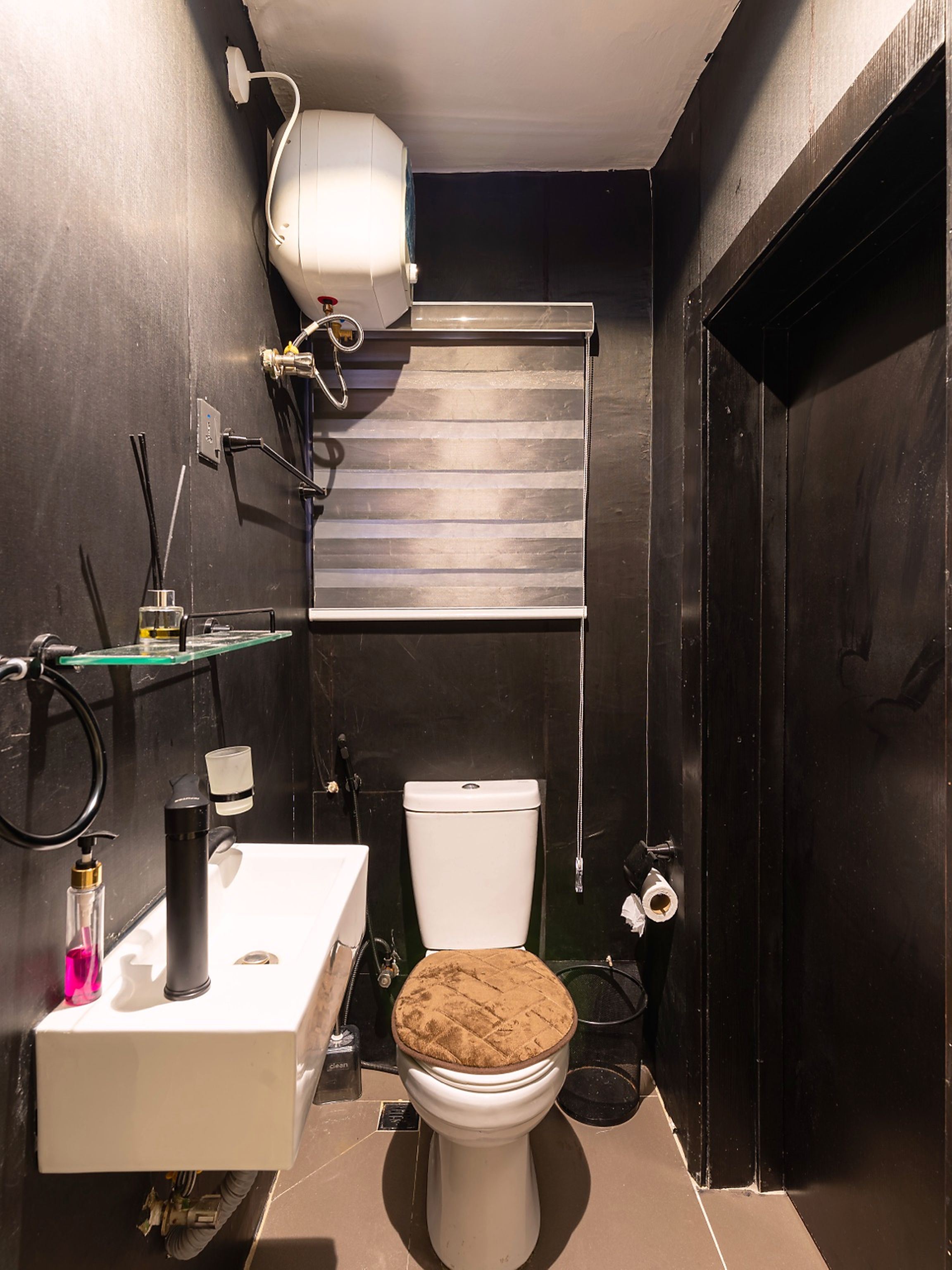 Casa de banho compacta com sanita, lavatório e chuveiro.