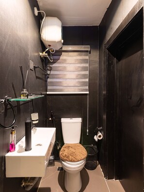 Ein kleines Badezimmer mit Toilette, Waschbecken und Duschkopf.